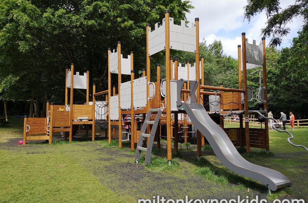 Large castle themed climbing frame with wavy slide in the play area at Daventry Country Park