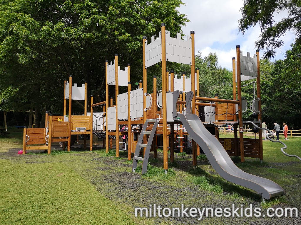 Large castle themed climbing frame with wavy slide in the play area at Daventry Country Park