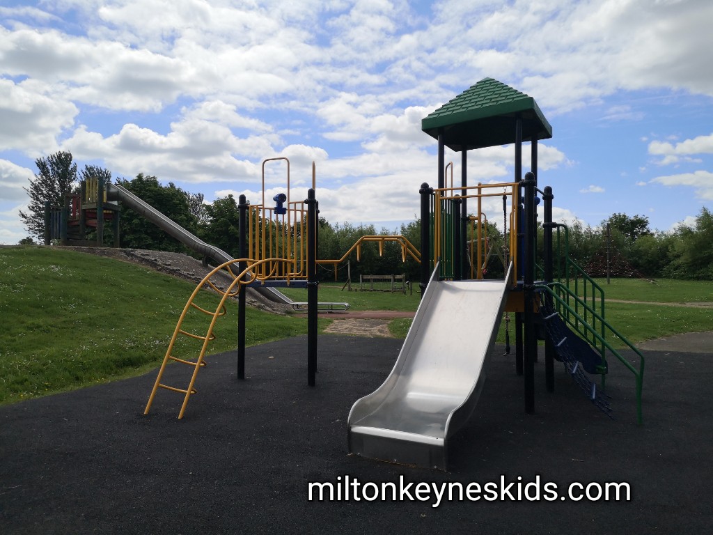 Climbing frame with a small slide, with a large slide in the background
